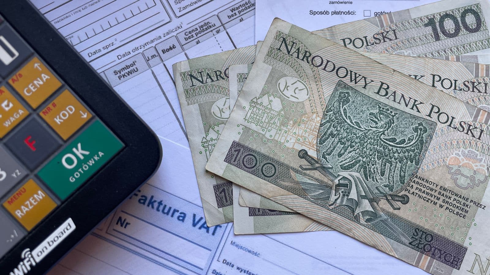 Banknoty stuzłotowe, faktura VAT i kalkulator - liczenie kosztów pomocy prawnej